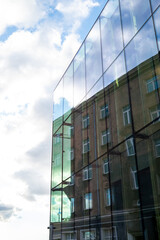 Obraz premium A fragment of a mirror-glass building reflecting the opposite structure, creating the illusion that the building is wrapped in a transparent glass envelope. 
