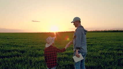 Father son shaking hands on field. Father child walk on field, sky sunset. Family farming business. Kid boy, dad go together, field corn sprouts. Agricultural industry. Growing corn, organic food