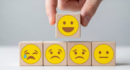 Hand selecting happy face wood block from a set of sad faces isolated on white background