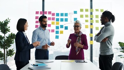 Diverse business team collaborating on project strategy brainstorming ideas with colorful sticky notes on a glass whiteboard in a modern office meeting room Project - Powered by Adobe
