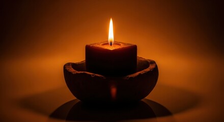 A single lit candle in a rustic bowl, casting a warm glow in the darkness