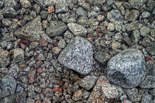Colorful wet pebbles and stones under clear water forming natural textured background