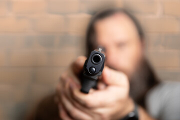A man with a gun is holding it up to his face