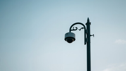 Modern Surveillance Camera on Streetlight Against Sky
