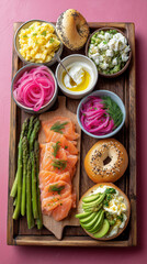 Gourmet lox and bagel brunch platter with fresh ingredients. Vertical flat lay of smoked salmon, cream cheese, avocado, and asparagus on a pink background