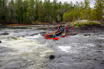 Team of white water canoeists work to get their boats past a rapid on the Madawaska River in Ontario