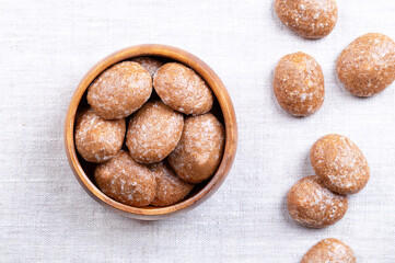 Gingerbread cookies, sugar glazed Christmas cookies, in a wooden bowl, on linen. Spice cookies, made of flour, sugar, and eggs, flavored with ginger, nutmeg, cloves, and cinnamon. From above. Photo
