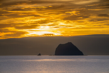 The sun rises over the sea, casting a beautiful golden light on the Keelung Islet and Little Keelung Islet near the Waimushan coastline in Keelung, Taiwan.