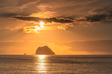 The sun rises over the sea, casting a beautiful golden light on the Keelung Islet and Little Keelung Islet near the Waimushan coastline in Keelung, Taiwan.