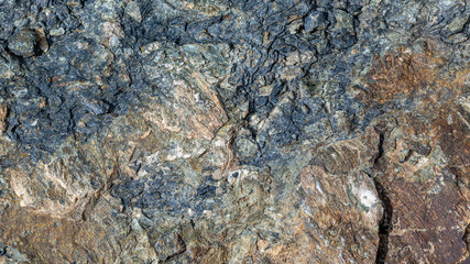 Close-up view captures rough, textured rock under natural sunlight. Earthy tones and details highlight the beauty of outdoor landscapes in daytime.