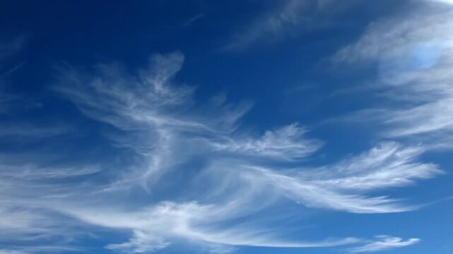 Vibrant Blue Sky with Wispy Cirrus Clouds. Delicate, feathery white cloud formations against an azure backdrop, clear weather.