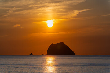 A breathtaking sunrise video from Waishuangxi Beach Keelung Taiwan. The sun rises over Keelung Islet creating a mystical and dramatic sky with golden orange tones.