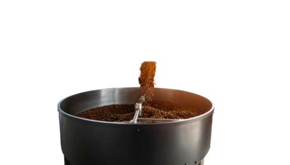 Coffee beans pouring from above into a metal bowl, captured against a stark black background