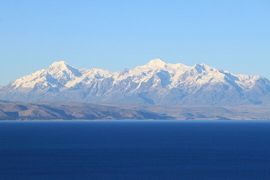 Panoramic view from Isla del Sol (Island of the sun) over seemingly endless Lake Titikaka in Bolivia to andean mountain ridge of Cordillera Real with snow covereded peaks and glaciers.