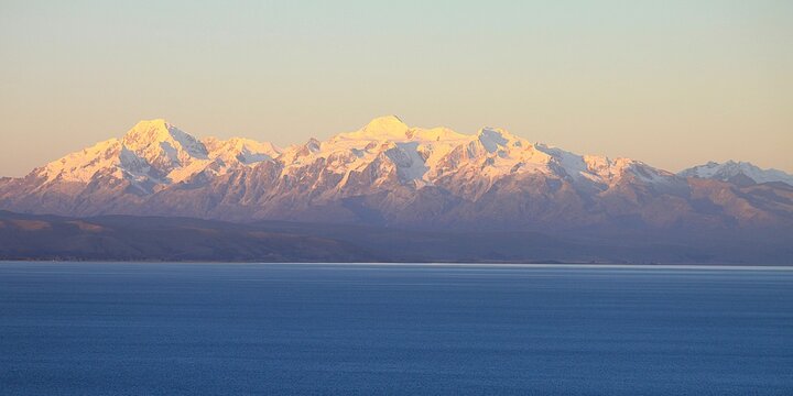Panoramic view from Isla del Sol (Island of the sun) over seemingly endless Lake Titikaka in Bolivia to andean mountain ridge of Cordillera Real with snow covereded peaks and glaciers. Twilight photo.
