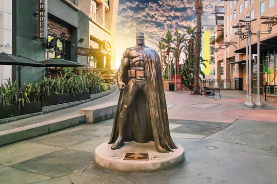 Burbank, California, USA - 09, 02, 2025: The iconic bronze Batman statue based on Jim Lee's 'Hush' design standing watch over the AMC Walkway in downtown Burbank during a dramatic golden hour sunset