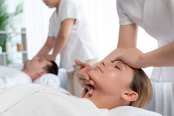 Fototapeta premium Caucasian couple enjoying relaxing anti-stress head massage and pampering facial beauty skin recreation leisure in dayspa modern light ambient at luxury resort or hotel spa salon. Quiescent