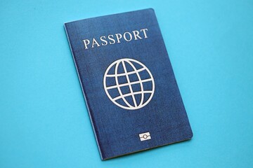 Generic passport book on light blue paper background close up. Travel document on blue surface