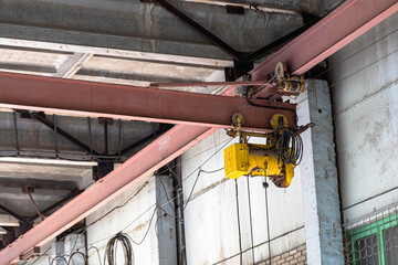 Industrial overhead crane features a bright yellow hoist suspended from robust steel beams, showcasing the mechanical structure and functionality within a spacious warehouse environment