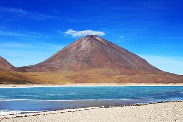 Lenticular cloud covers summit crater of colorful stratovolcano Cerro Licancabur, saline lake Laguna Verde at foot of mountain in Eduardo Avaroa Andean Fauna National Reserve in Cordillera Occidental. © Koapan