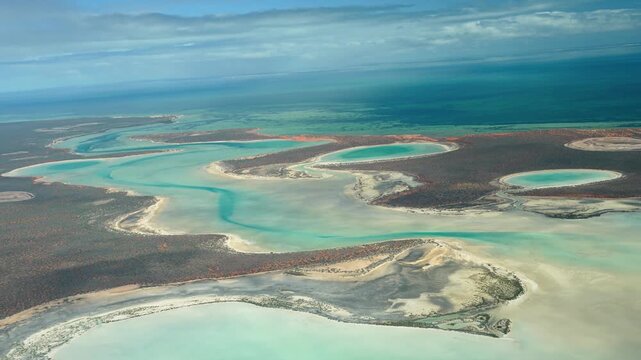 Drone-style perspective from airplane flying over Useless Loop salt fields and arid coastal landscape