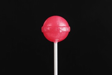 Isolated red lollipop candy sweet treat on white stick against black background