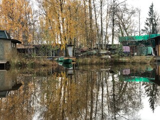 Boats and boathouses on the lake shore are reflected in the clear water