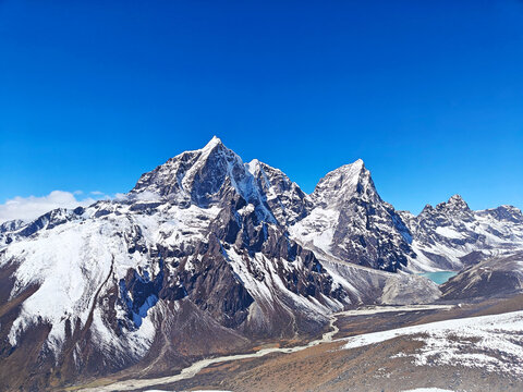 Snow-covered peaks rise majestically against a bright blue sky showcasing nature's beauty. Nepal, Himalayas