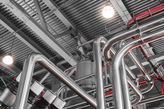 Stainless steel pipes attached to stainless steel tank with industrial food production machine, industrial concept background.