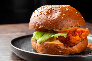 A close-up shot of a gourmet crispy chicken sandwich on a sesame seed brioche bun, with lettuce,...