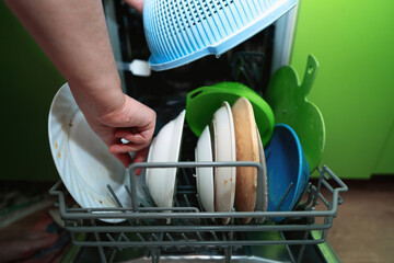 Female hands loading very dirty plates and dishes into a dishwasher for cleanin