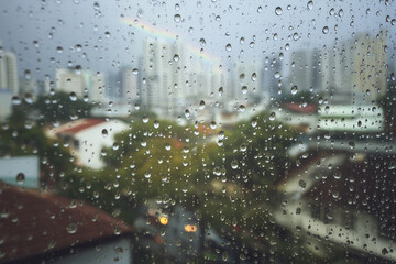 Equatorial Monsoon City Balcony Photovoltaics With Raindrops And Faint Rainbow Over Rooftops, Focus-Pull Look, Afternoon Downpour