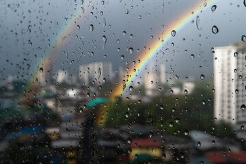 Equatorial Monsoon City Balcony Photovoltaics With Raindrops And Faint Rainbow Over Rooftops, Focus-Pull Look, Afternoon Downpour