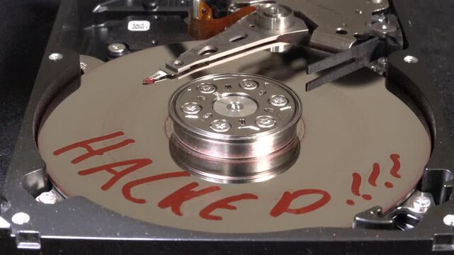 Opened hard drive with flashing light effects, HACKED written on the surface and starting to spin