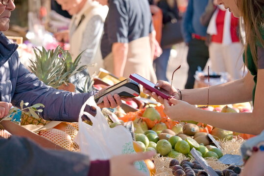 Client qui paye son achat de fruits et l&eacute;gumes frais sur un march&eacute; ensoleill&eacute; de Nice