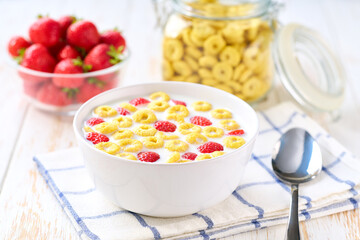 Healthy breakfast for kids with corn rings and strawberry on a light kitchen table, selective focus.