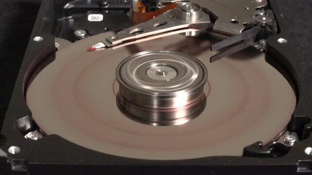 Open hard drive spinning with flashing light effects, stopping rotation, and HACKED appearing on the surface 
