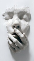 Sculpture of a serene face partially hidden by hands on a plain background