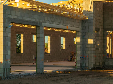 Warm sunlight illuminates garage interior and part of the roof a single-family house under construction during golden hour on an autumn morning in a suburban residential development in Florida