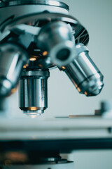 Close-up of metal microscope lens with glowing light on sample slide