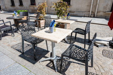 Tables with chairs for cafe outside on the street in summer city.