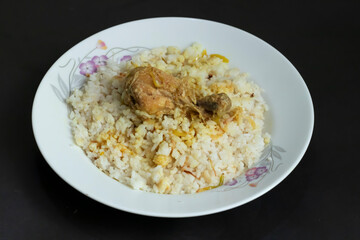 homemade chicken polao and rice, beautifully presented on a floral plate against a dark backdrop. Ideal for culinary inspiration.