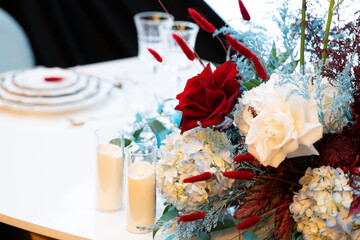 Elegant wedding table floral arrangement with fresh roses, peonies, and greenery. Romantic centerpiece decoration for a wedding reception or banquet, featuring soft pastel colors and delicate blooms c