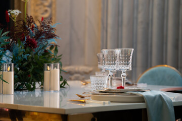 Elegant wedding table setting with crystal glasses, fine china plates, and delicate floral arrangement. Luxury wedding decor with sparkling glassware and refined tableware, creating a wedding decor