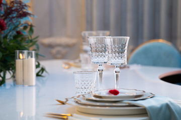 Elegant wedding table setting with crystal glasses, fine china plates, and delicate floral arrangement. Luxury wedding decor with sparkling glassware and refined tableware, creating a wedding decor