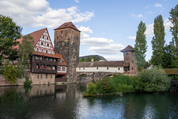 Fototapeta premium Picturesque view of Henkerhaus Museum, Wasserturm, and the Henkersteg bridges in Nuremberg, Bavaria, spanning the Pegnitz River amid charming medieval architecture.