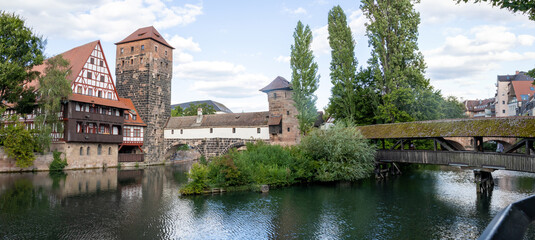 Obraz premium Picturesque view of Henkerhaus Museum, Wasserturm, and the Henkersteg bridges in Nuremberg, Bavaria, spanning the Pegnitz River amid charming medieval architecture.