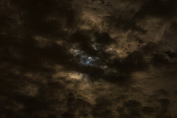 Moon shines through clouds with dramatic blue and gold colored halo 