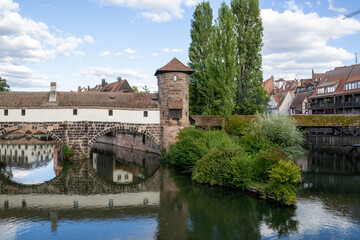 Picturesque view of Henkerhaus Museum, Wasserturm, and the Henkersteg bridges in Nuremberg, Bavaria, spanning the Pegnitz River amid charming medieval architecture.