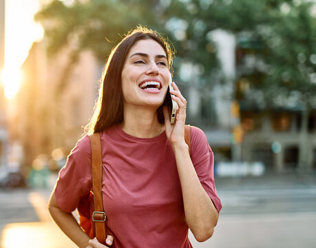Young woman enjoys sunny day while using smartphone in urban setting, highlighting her joy and connection to the world around her